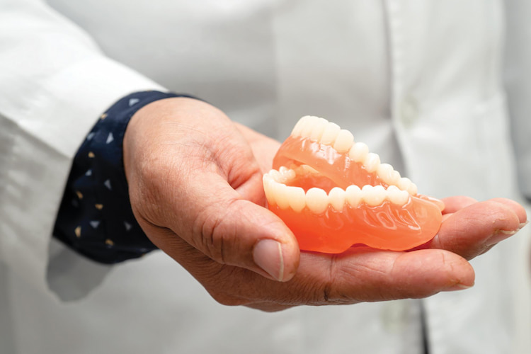a dentist's hand holding a pair of dentures