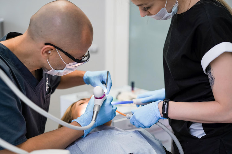 a dentist with his assistant are performing root canals for a patient.