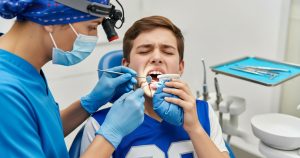 A dentist examines a boy holding an ice pack to his mouth demonstrating sports related dental injuries.